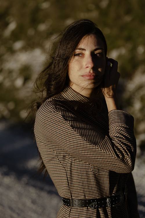 Ritratto femminile su pendio di montagna, donna che guarda lontano immersa in luce calda.