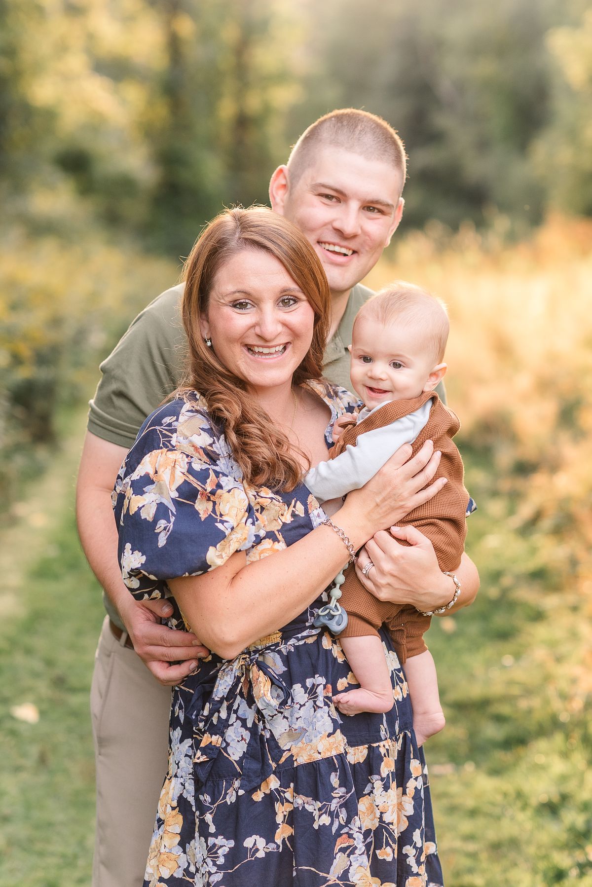 Husband and wife cuddled together with their baby and smiling
