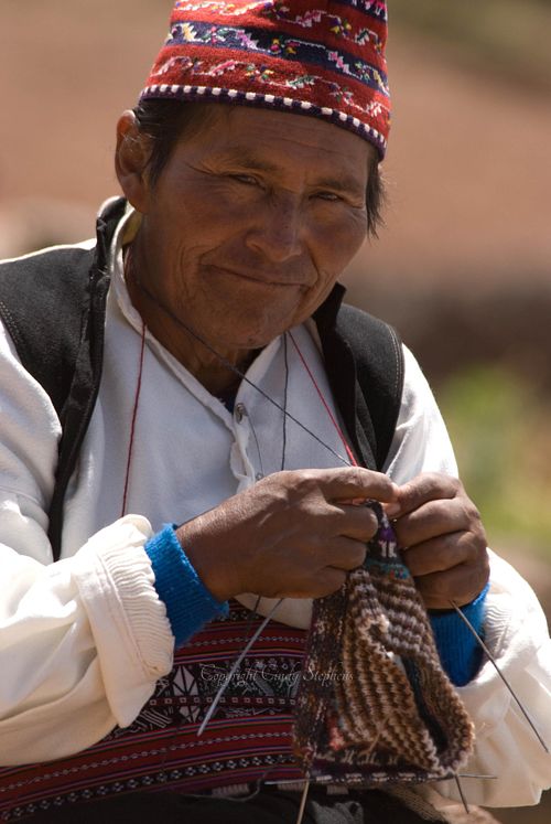 Taquileño man in traditional dress sewing a textile on Taquile Island, Lake Titicaca, showcasing the rich textile art of Quechua culture