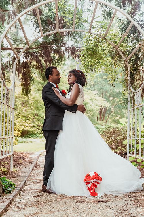 Bride and groom sharing a romantic moment under the garden arch at the Fayetteville Botanical Gardens, photographed by a editorial luxury Raeford NC wedding photographer.