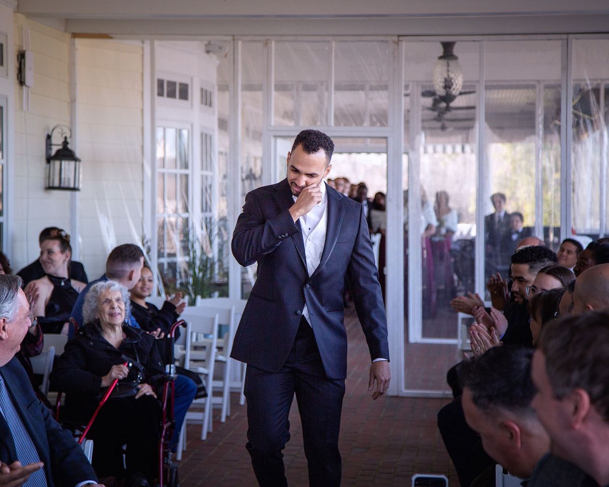 groom entering the the covered porch at baywood greens, giving a fist bump to his guests