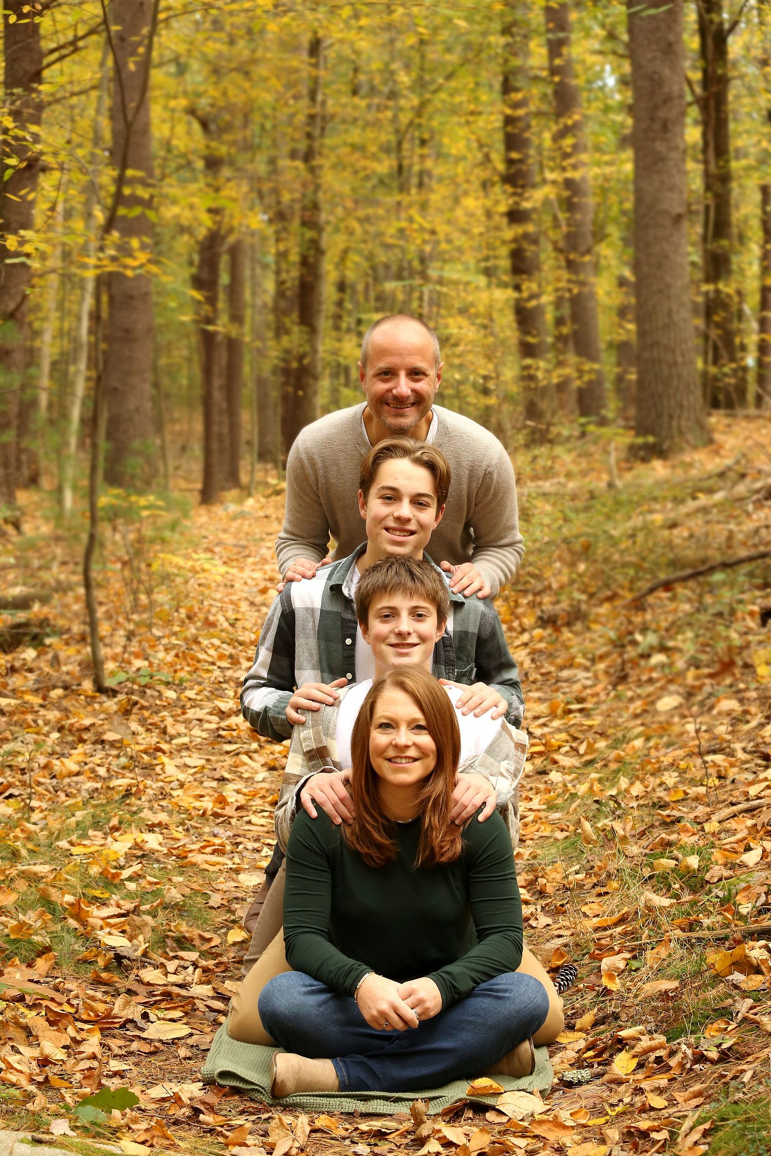 Family of four posing in the woods, stacked