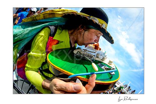 Horizontal color image of Randy Hansen in a tight outdoor ship deck close-up with a green guitar and vivid stagewear