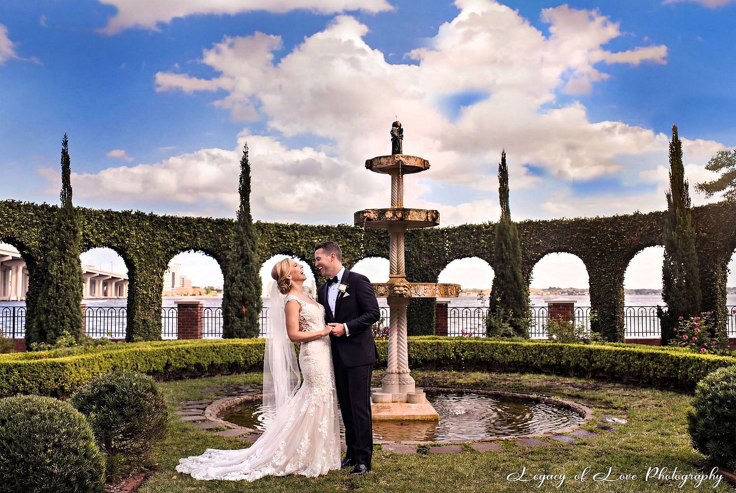 Elegant bride and groom laughing by the fountain at Epping Forest Yacht Club, a premier Jacksonville FL wedding photography location.