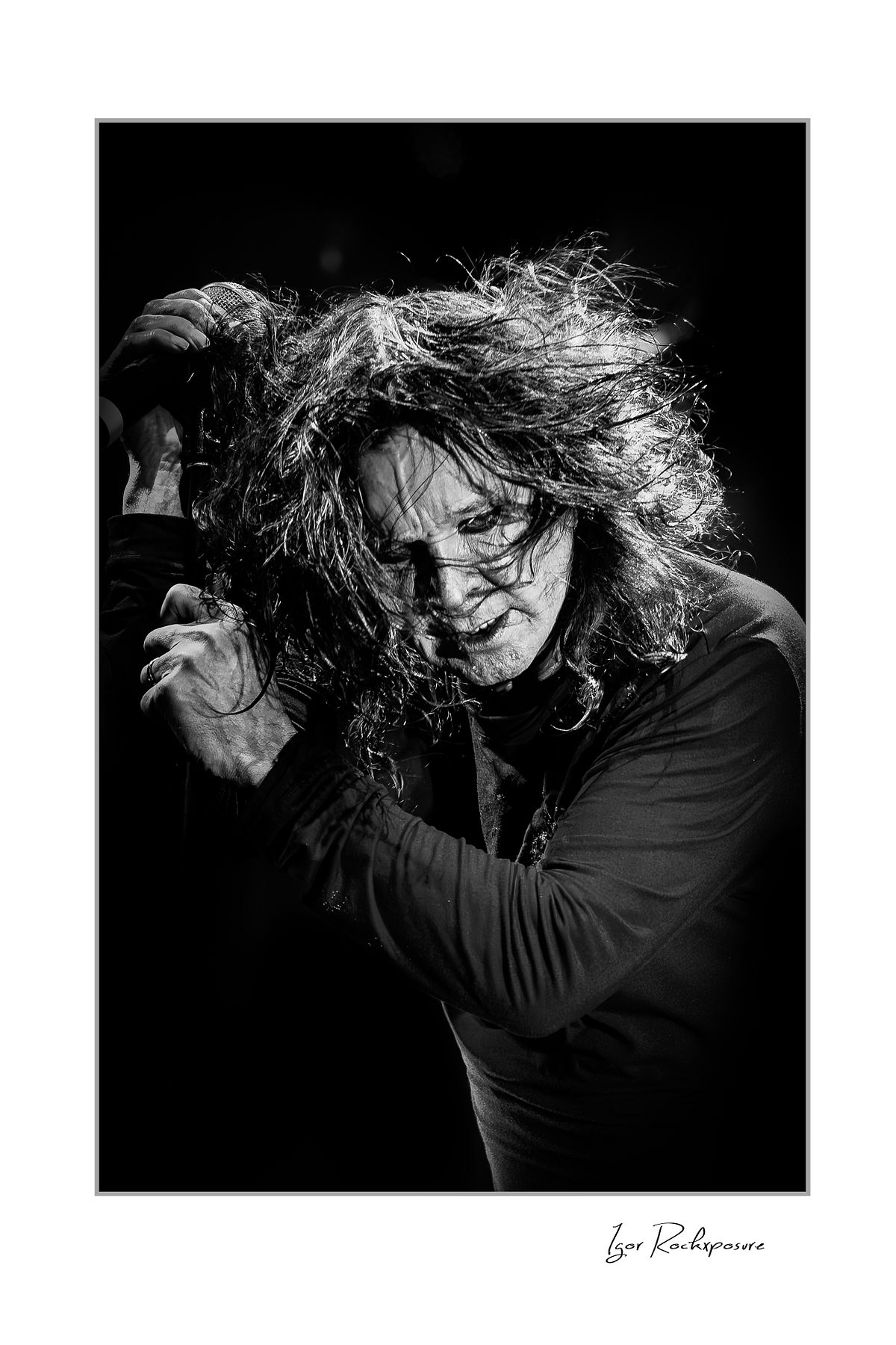 Black and white portrait of Ozzy Osbourne of Black Sabbath with windblown hair and intense expression during a live performance