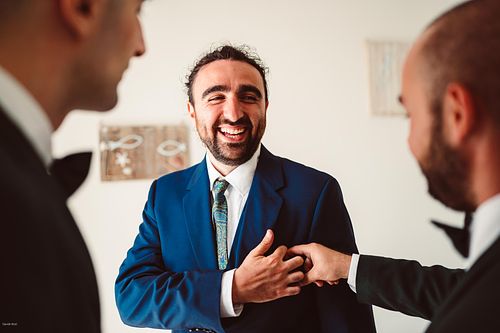 "sposo con abito blu che scherza con gli amici"