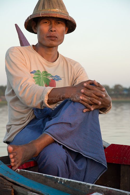 Fisherman sitting cross-legged in a traditional wooden canoe on Inle Lake, Myanmar, showcasing local fishing culture.