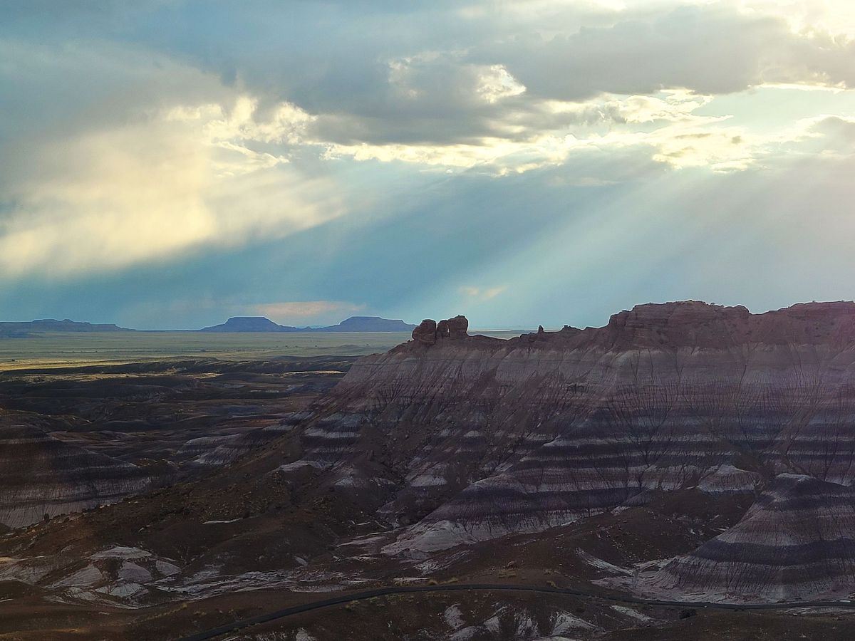 sun through the clouds overlooking the painted hills at petrified forest national park, arizona