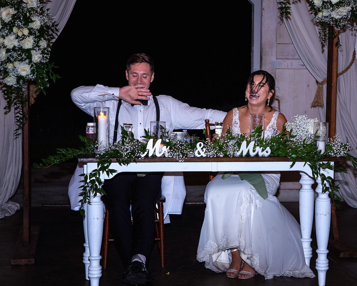 a candid photography of a couple sitting at the sweet-heart table at Kylan Barn in Delmar, Delaware