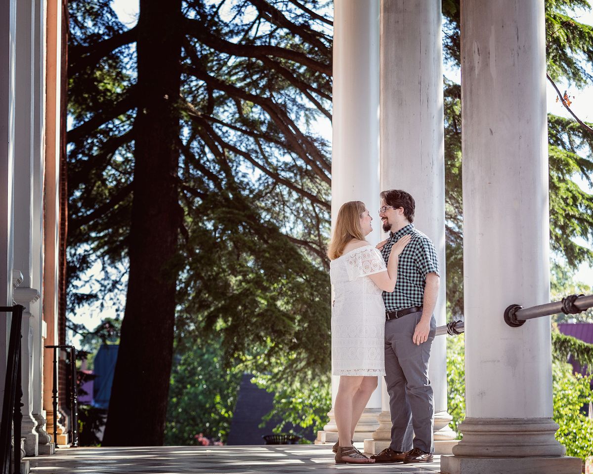 couple in front of historical columns, the bride is having her arm on the grooms shoulder.