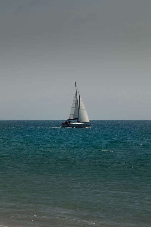 Mer turquoise avec voilier distant.