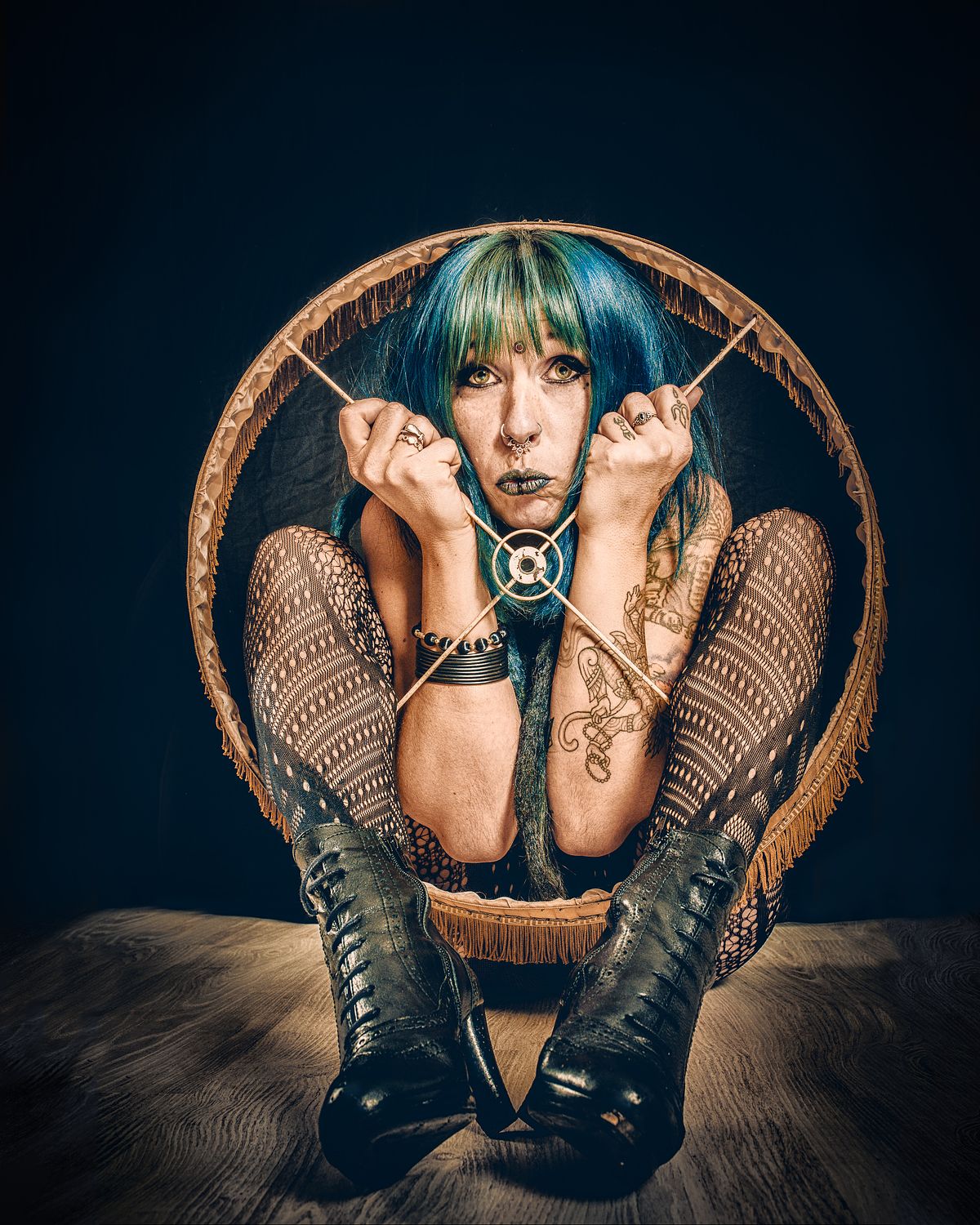 Portrait artistique d’une femme aux cheveux colorés accroupie dans un abat-jour, symbolisant l’enfermement psychologique, la prison mentale et la lutte pour se libérer — œuvre de Pascal Yennis, Namur, Belgique.