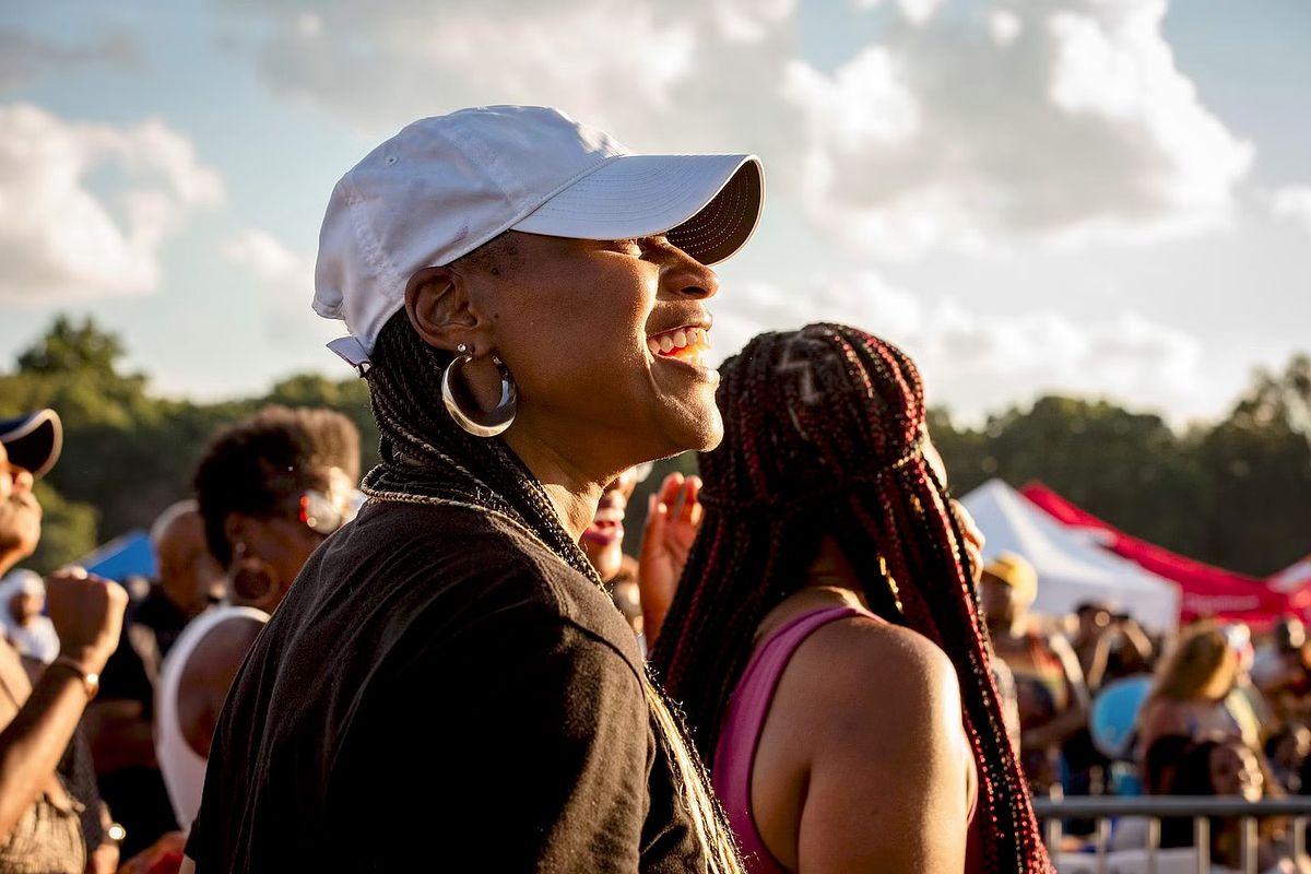 Documentary-style event photography of a woman smiling in the crowd at a Philadelphia summer festival, capturing authentic emotion, community energy, and cultural vibrancy.