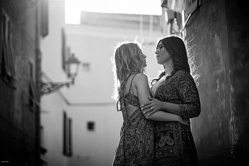 "coppia si guarda abbracciata per le strade di Alghero"