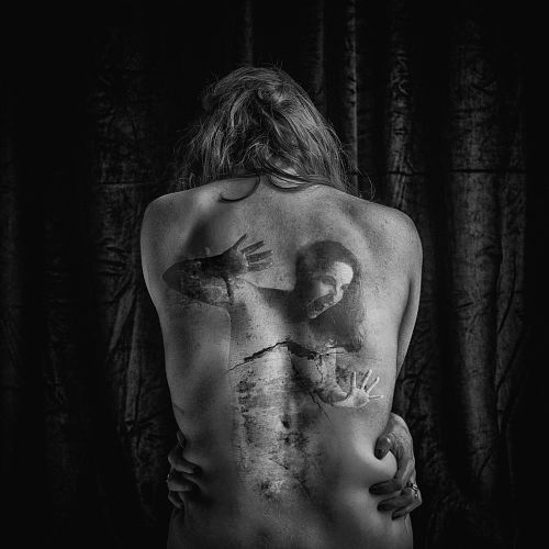Photographie en noir et blanc d&rsquo;une femme de dos, avec le double-expos&eacute; d&rsquo;une autre femme emprisonn&eacute;e dans son dos, symbolisant les &eacute;motions refoul&eacute;es et la souffrance int&eacute;rieure