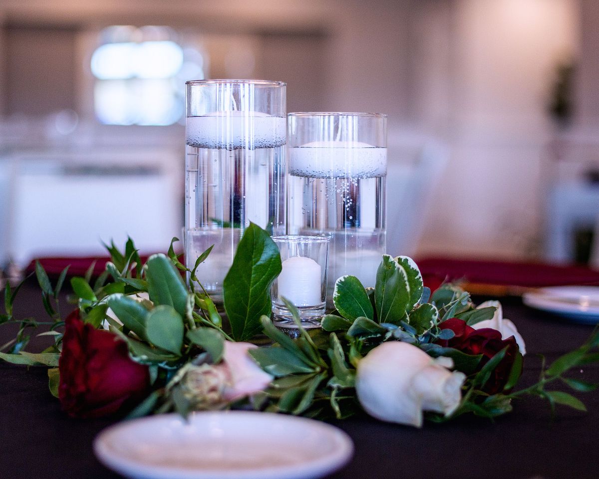 table setting with a plate in the foreground and candles and roses in the background at baywood, milford, de