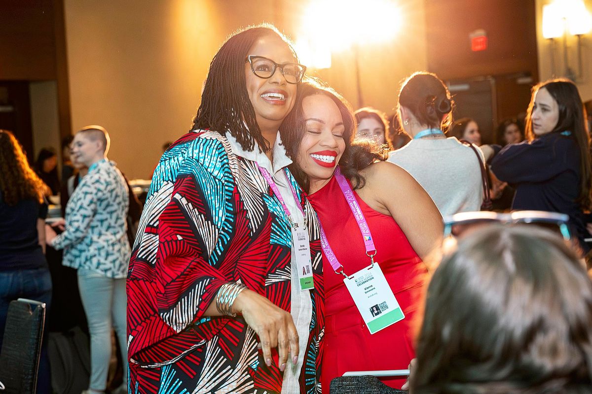 Corporate event photography capturing a warm embrace during a networking mixer at the Grace Hopper Celebration 2024 in Philadelphia, highlighting leadership, authenticity, community, and connection within the tech industry.
