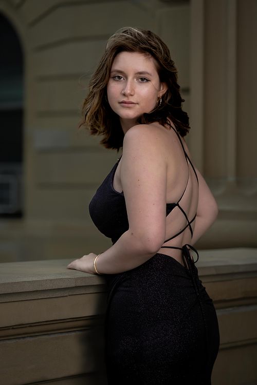 Young woman looking over her shoulder in her grad dress at the Alberta Legislature.