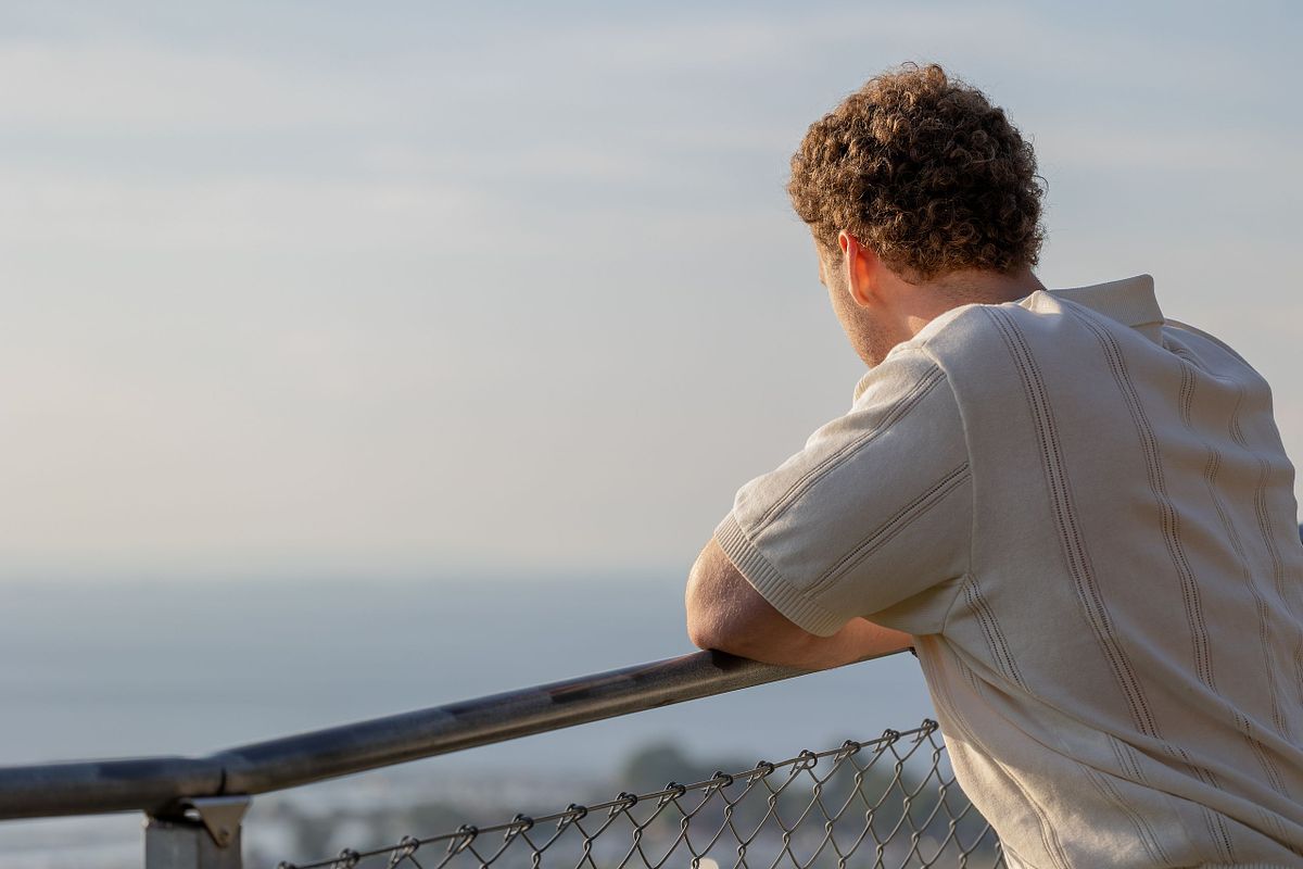 Man i profil som lutar mot r&auml;cke och blickar ut &ouml;ver vattnet, redaktionell stil