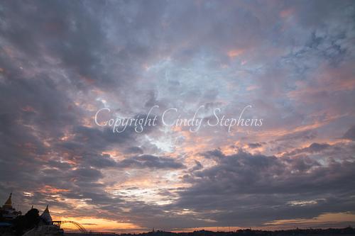 Pink skies at sunset with a bridge and stupas