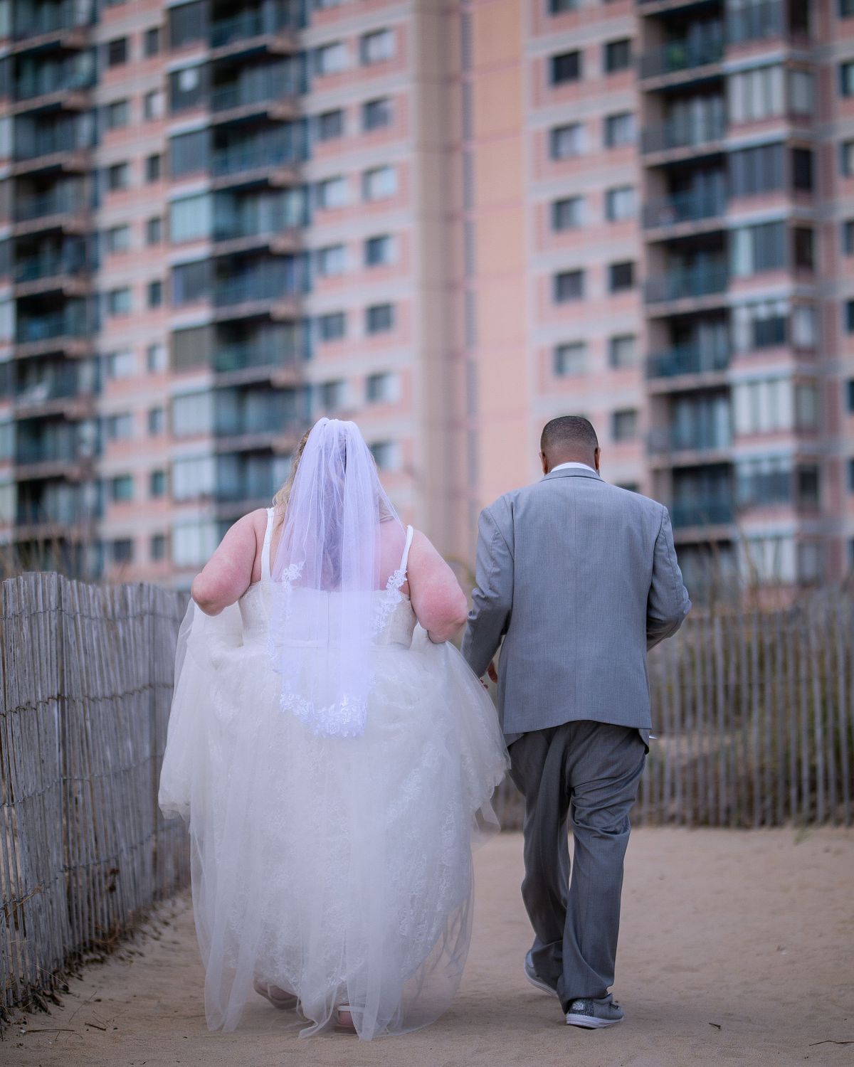 bride and groom walking towards hotel after photo session during sunset hours in ocean city maryland