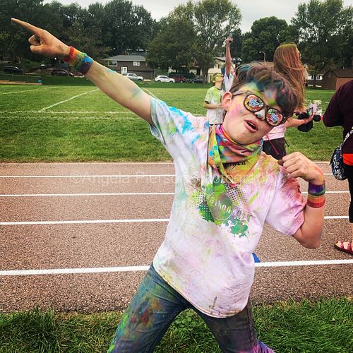 A boy poses covered in colorful dust