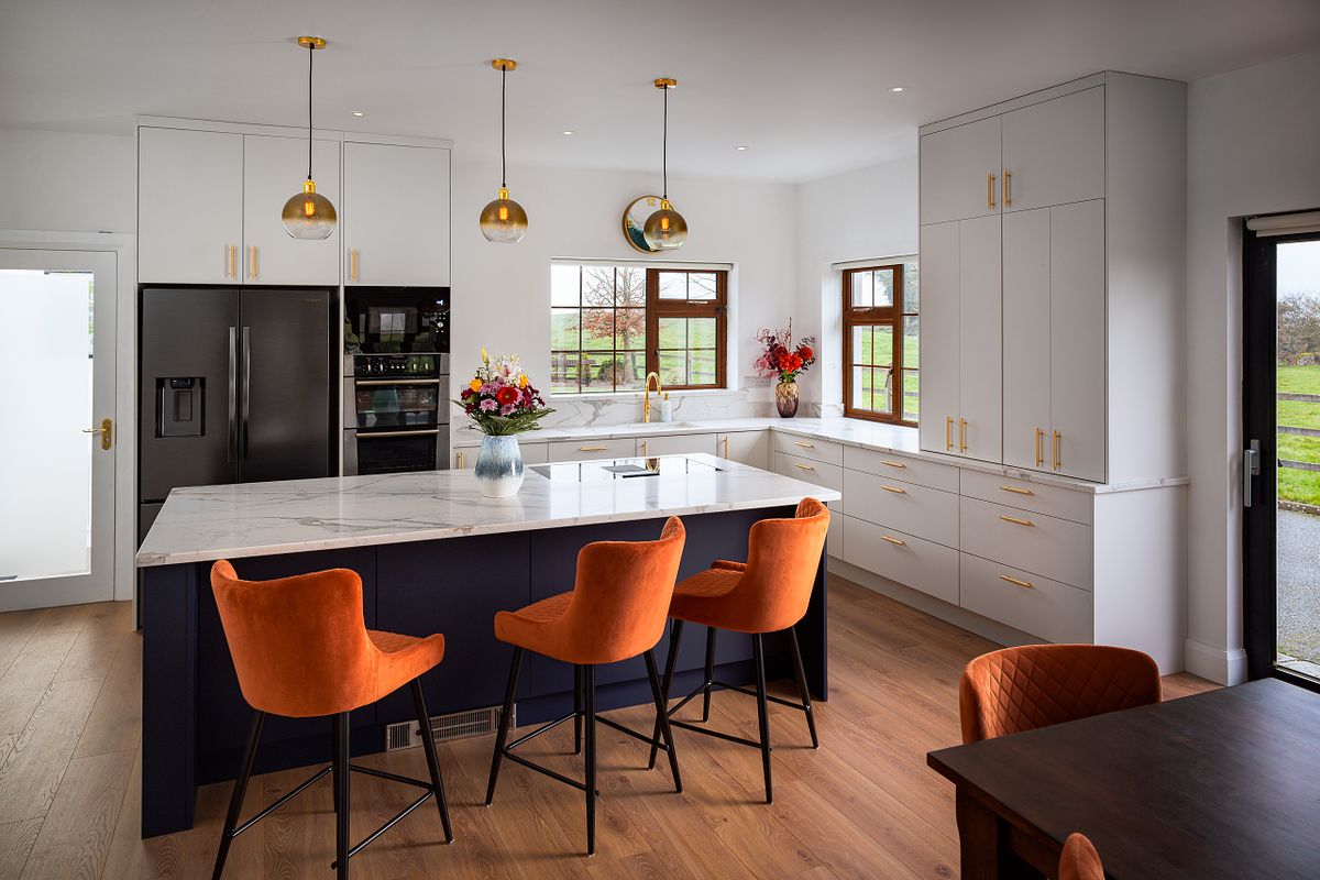 Interior of a large, modern kitchen with dark cabinets, a light-colored island, and a high ceiling with a skylight.