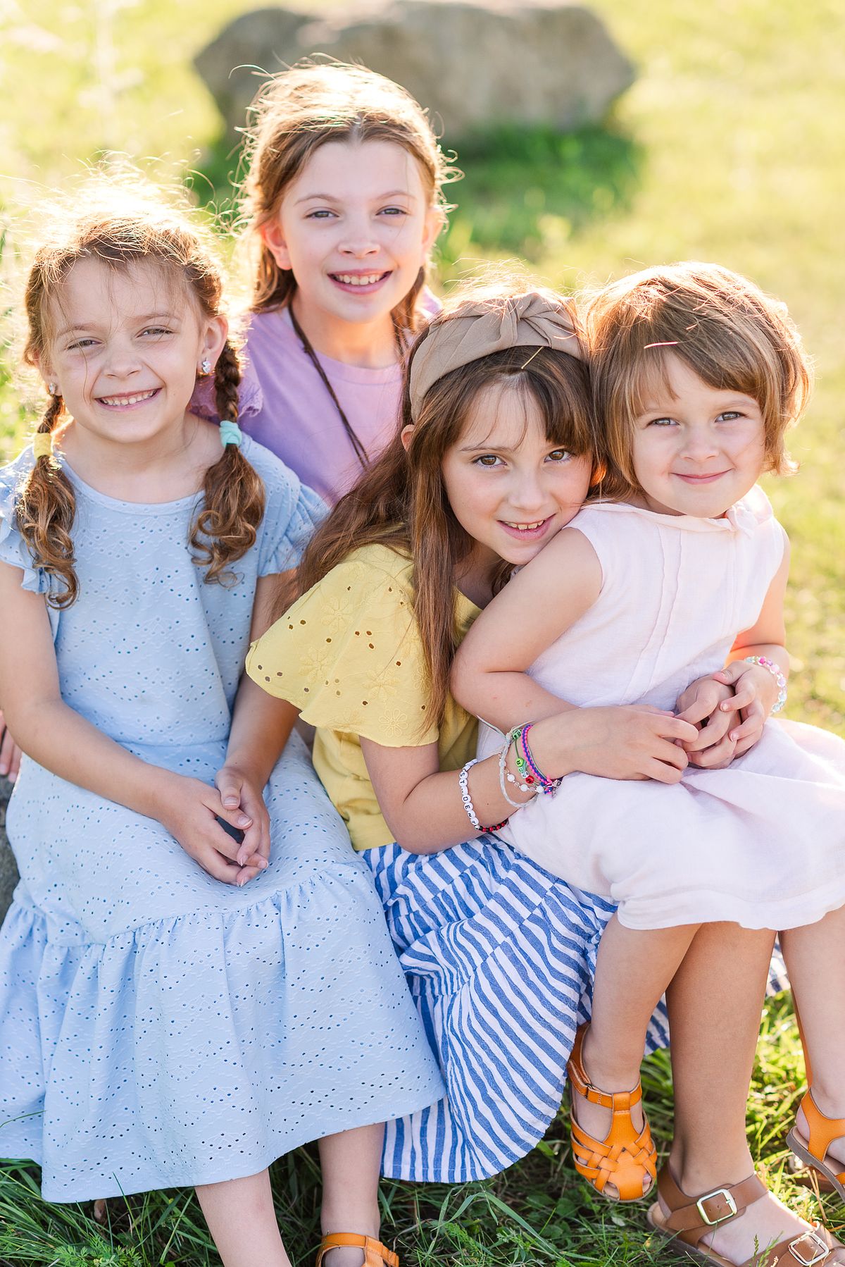 Four girls sitting on a large rock cuddling together in summer sunset glow at Cranberry Township Community Park