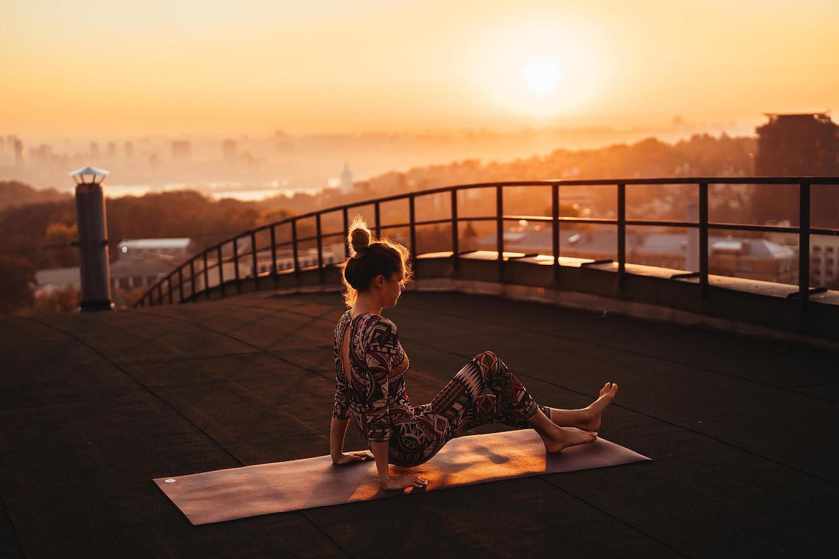 Woman doing yoga on the roof of a skyscraper in big city.