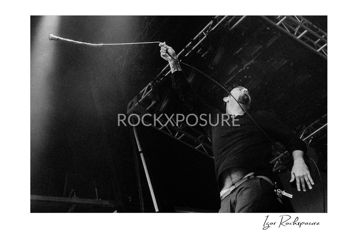 Horizontal concert photography of Chino Moreno performing on stage in black and white photography under dramatic stage lighting