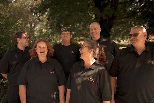 A group of people standing together outdoors, smiling and talking as a team