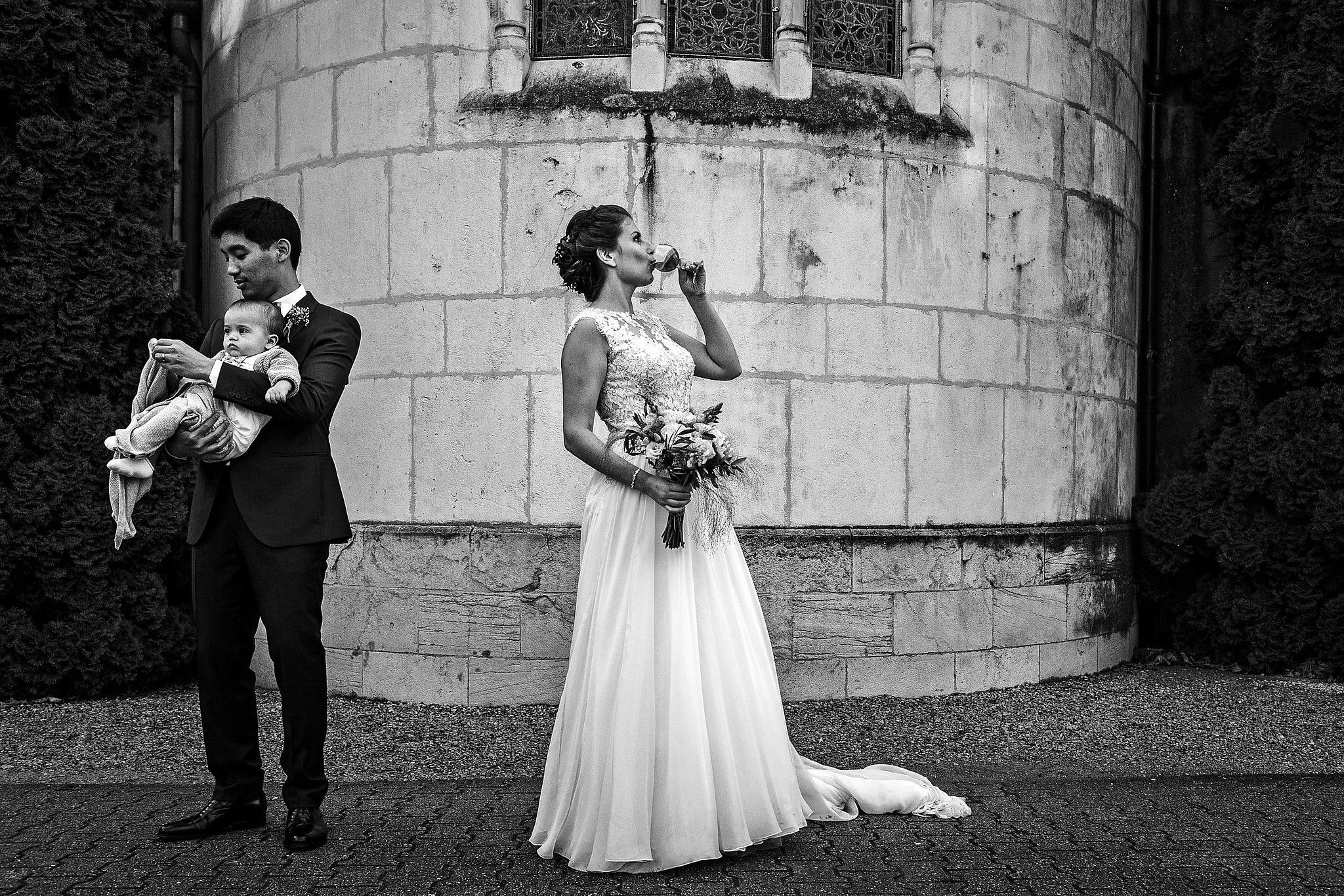 Mari&eacute;e qui boit et se d&eacute;salt&egrave;re durant la s&eacute;ance de photos de groupe pendant que son mari rhabille un enfant captur&eacute; par S&eacute;bastien CLAVEL photographe de Mariage &agrave; Lyon et Gen&egrave;ve