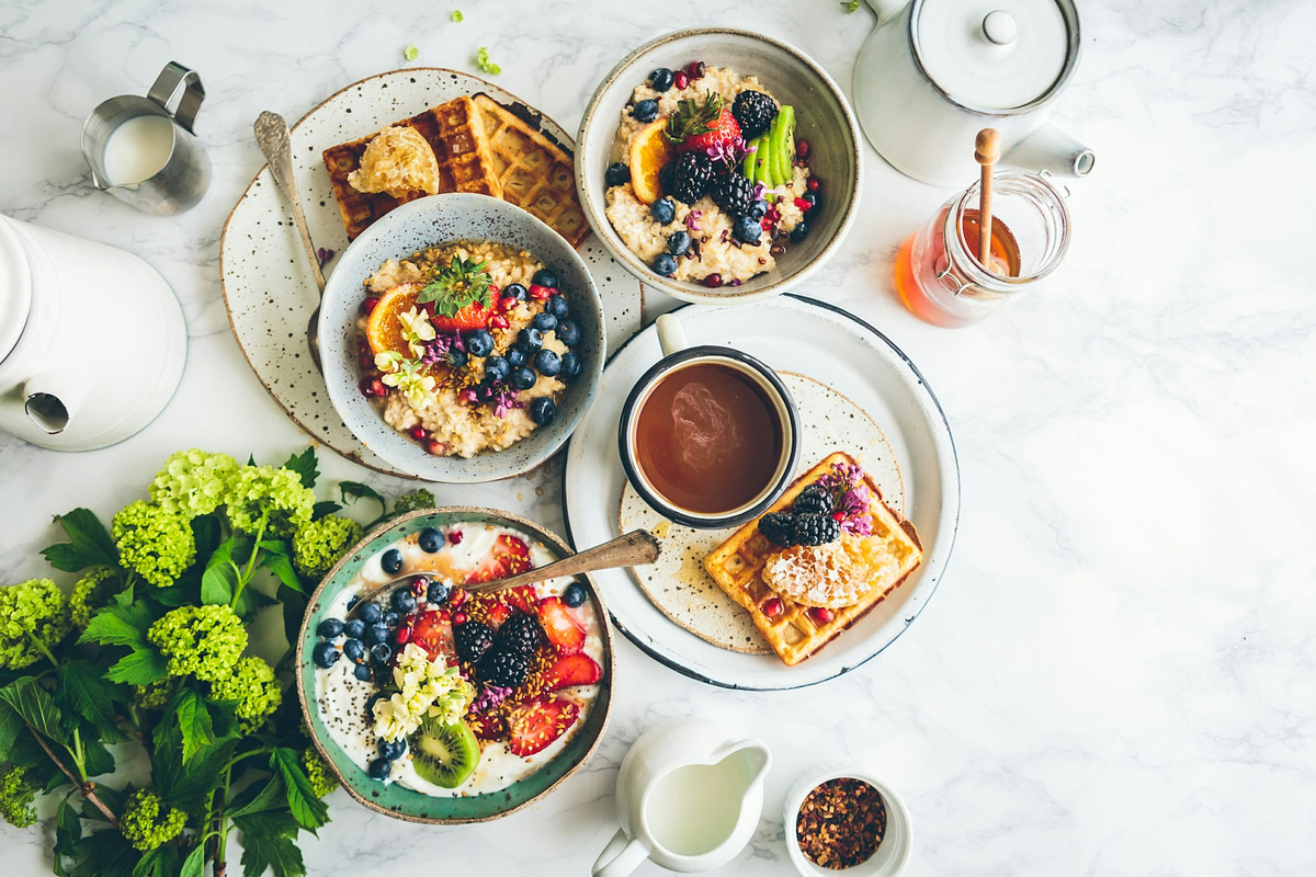 una colazione sana con waffle, ciotole di frutta e tè su un tavolo di marmo bianco
