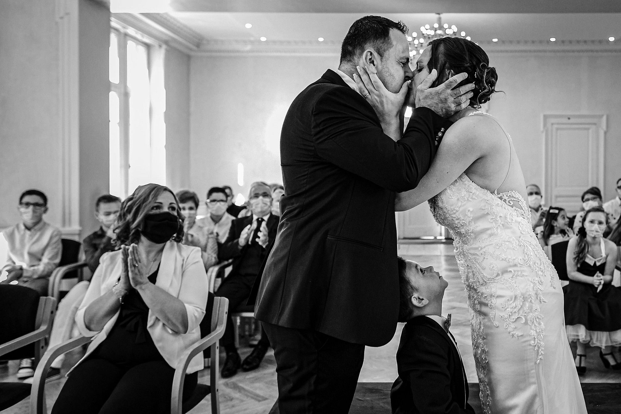 Couple de mari&eacute;s qui s'embrassent devant leurs invit&eacute;s et leurs enfants &agrave; la mairie captur&eacute; par S&eacute;bastien CLAVEL photographe de Mariage &agrave; Lyon et Gen&egrave;ve