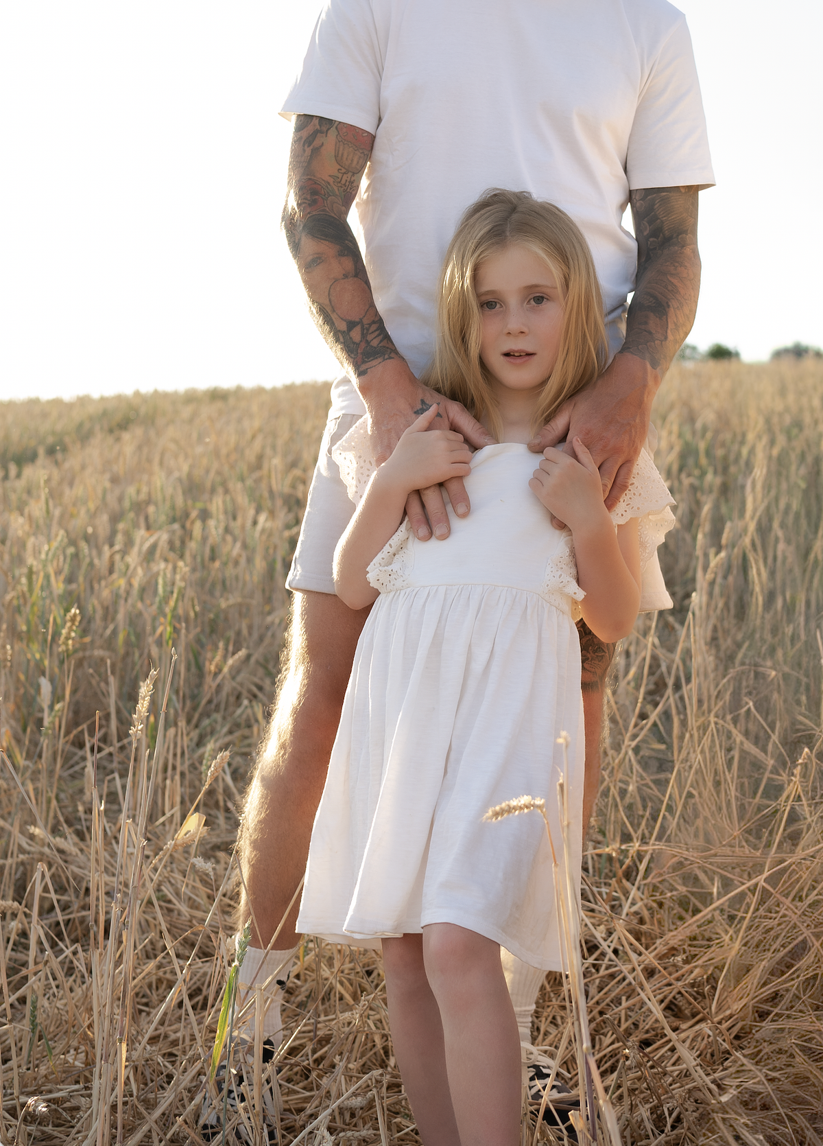 Father cradling daughter in golden wheat field, children's campaign photography Northamptonshire