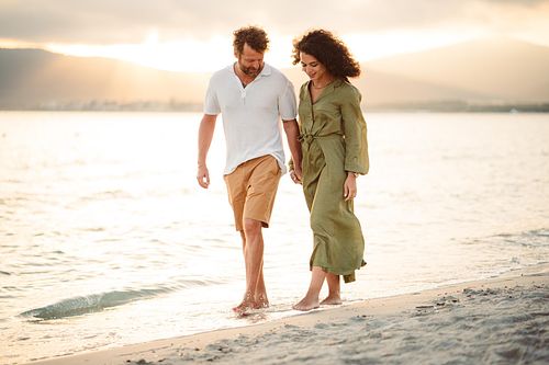 "coppia passeggia tenendosi per mano in spiaggia ad Alghero"