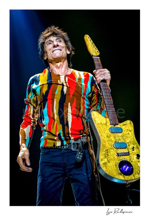 Vertical color image of Ronnie Wood of The Rolling Stones holding an electric guitar in a vivid close-up stage portrait