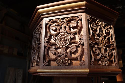 a close up of the upper part of the font in dramatic light that shows off the beauty of the carving