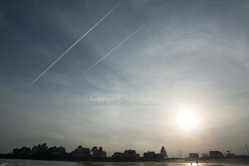 Individuals on a beach at twilight framed by a beautiful sky