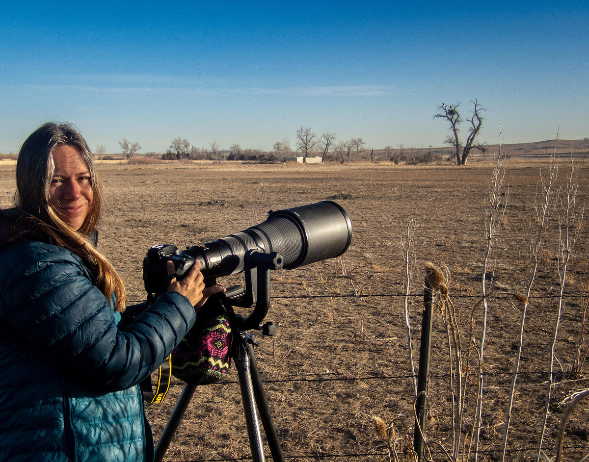 Lea Frye in the field holding her 600mm wildlife photography lens, affectionately nicknamed 'The Baby,' set up on a bald eagle nest.