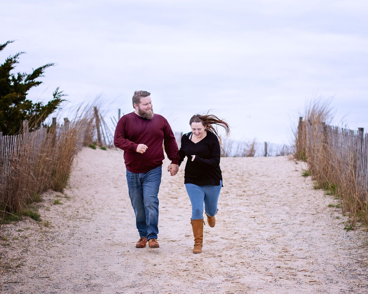 couple running on the beach holding hands in lewes de during autumn