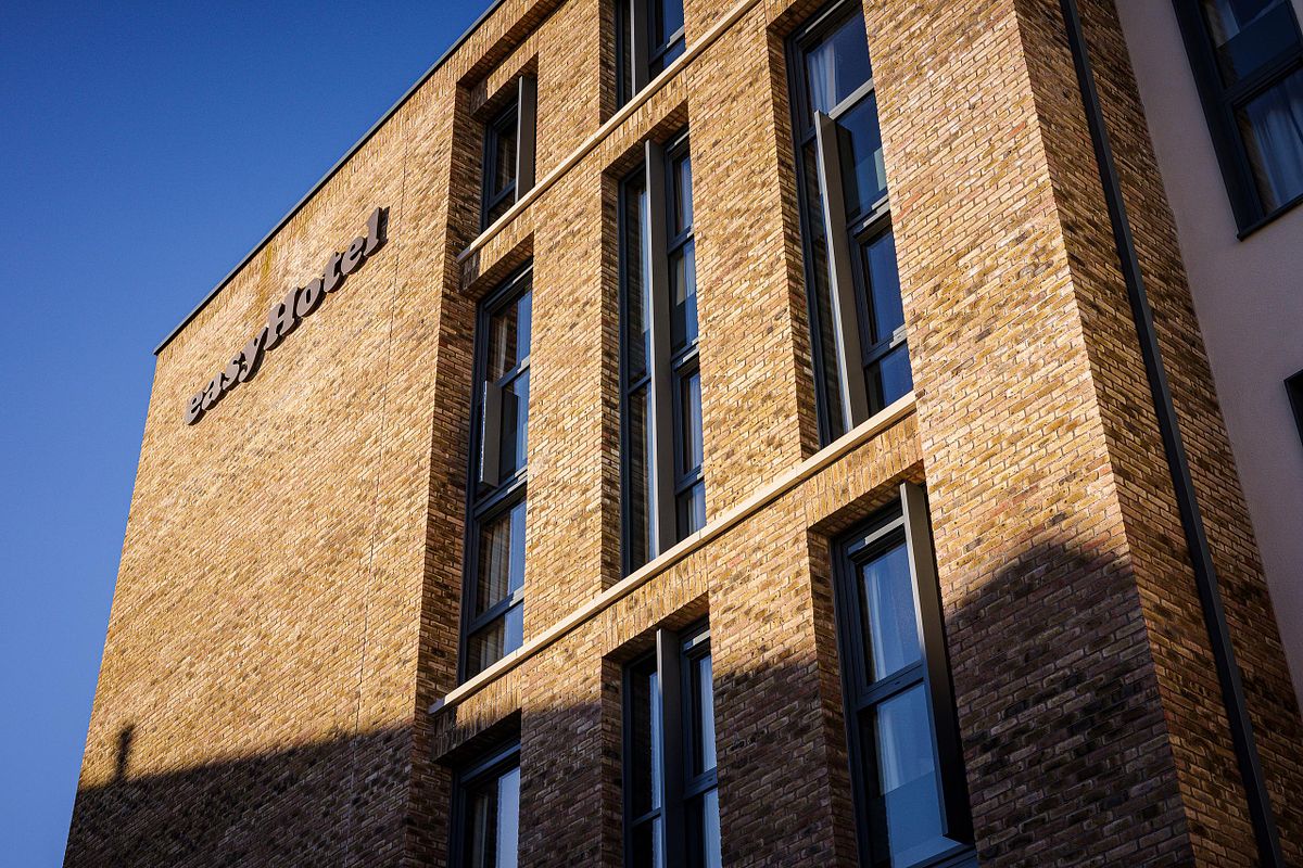 Exterior view of the Easy Hotel Dublin, showcasing its modern brick facade and tall, narrow windows. The 'easyHotel' logo is visible on the building. Clear blue sky in the background.