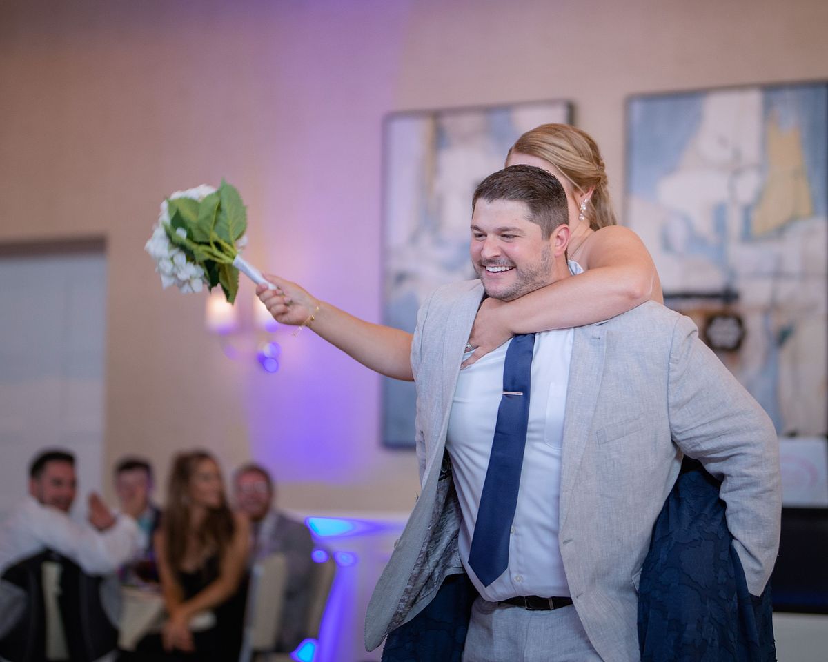 introduction of bridesmaid and groomsmen during the reception the hyatt in dewey beach, sussex county, de. the groomsmen is giving the bridesmaid a piggyback ride