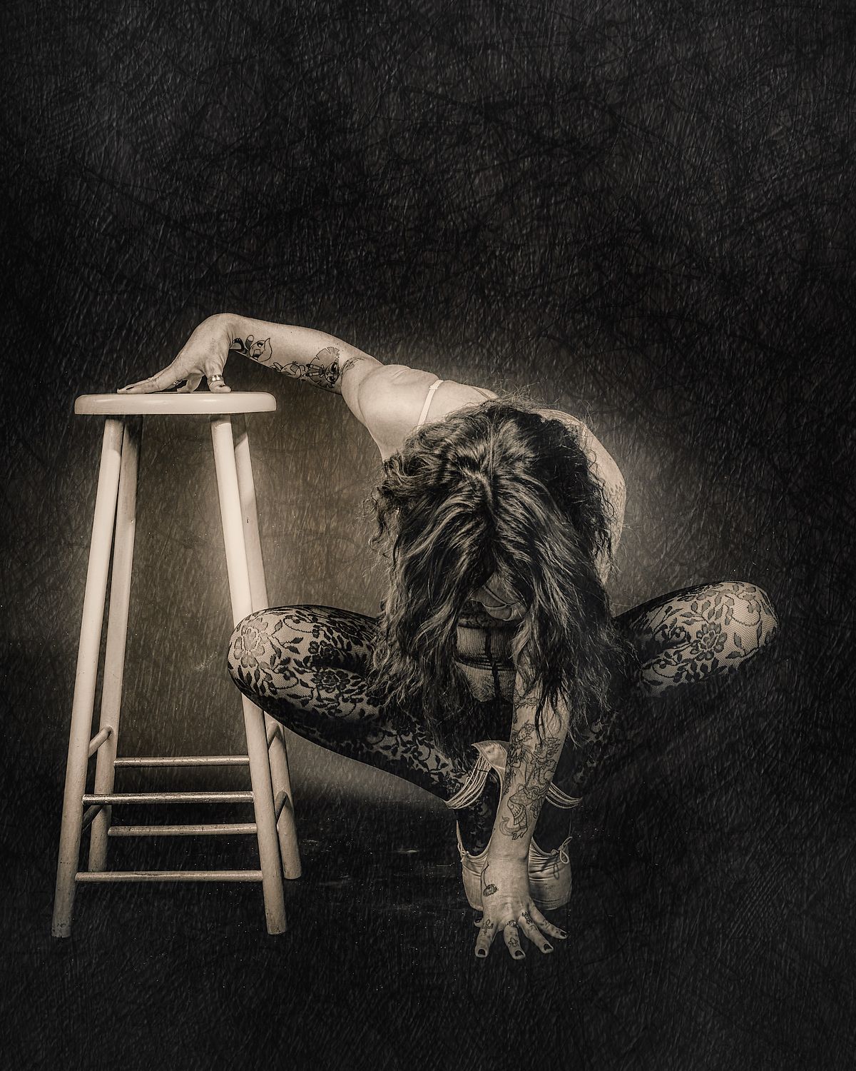 photo tarot Exhausted, femme accroupie sur tabouret, cheveux couvrant le visage, posture d'épuisement silencieux