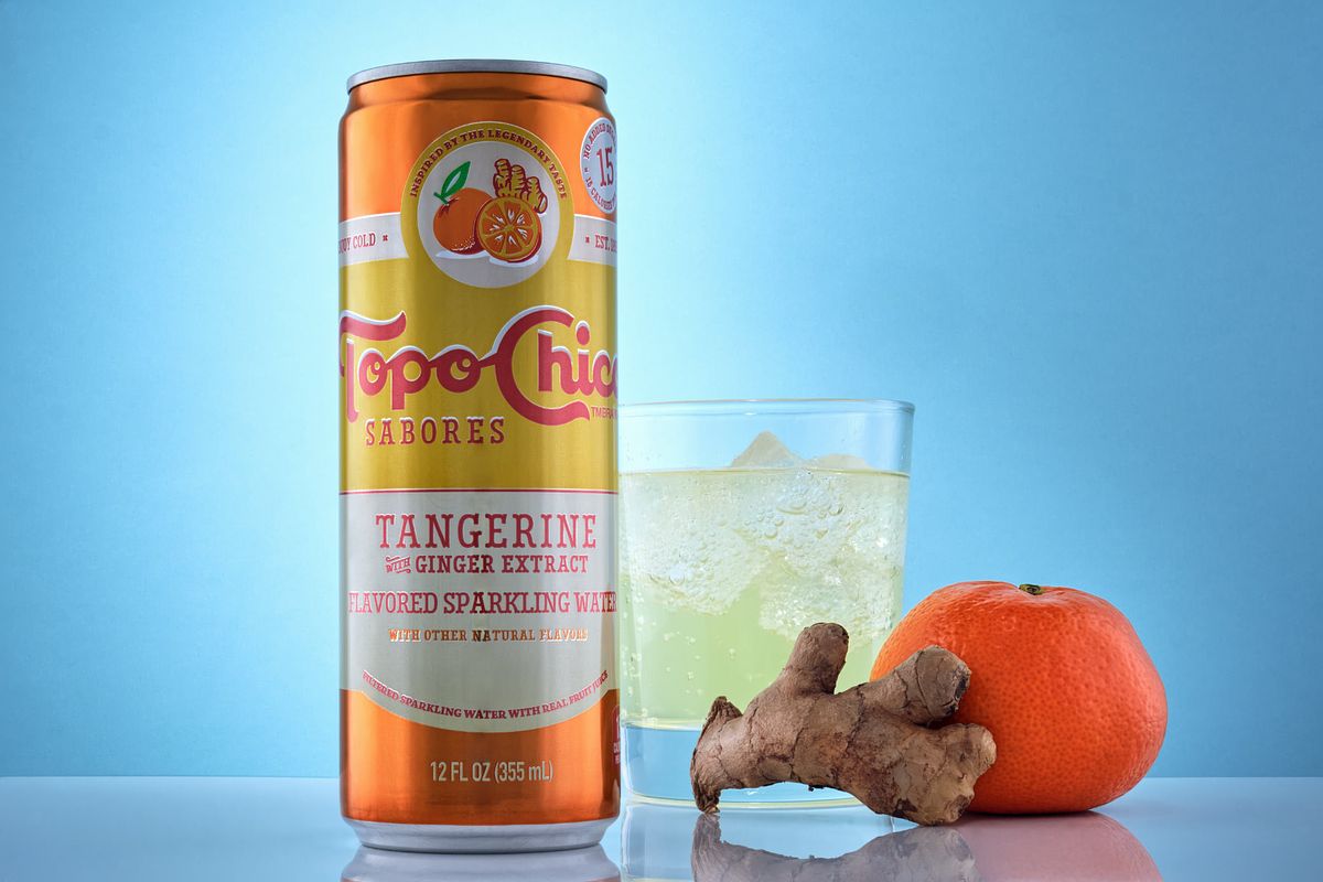Professionally lit seltzer can beside an iced cup, ginger and a tangerine.