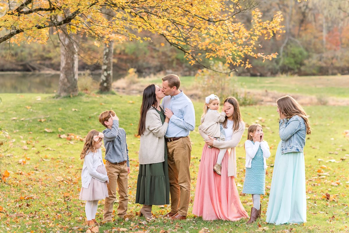 Husband and wife kissing and six children trying not to look or looking shocked  with Cranberry Township, PA newborn photographer