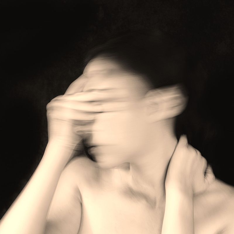 blurred image of a woman holding hands over eyes and neck