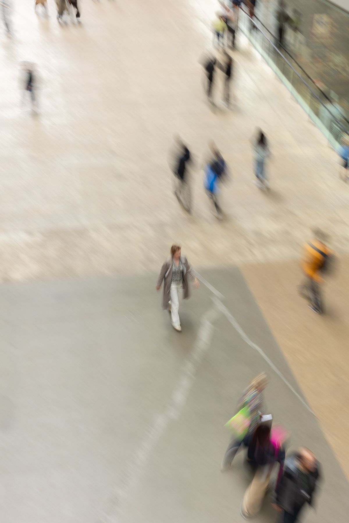 M&auml;nniskor i mjuk r&ouml;relse &ouml;ver stor betongyta sett uppifr&aring;n p&aring; museum