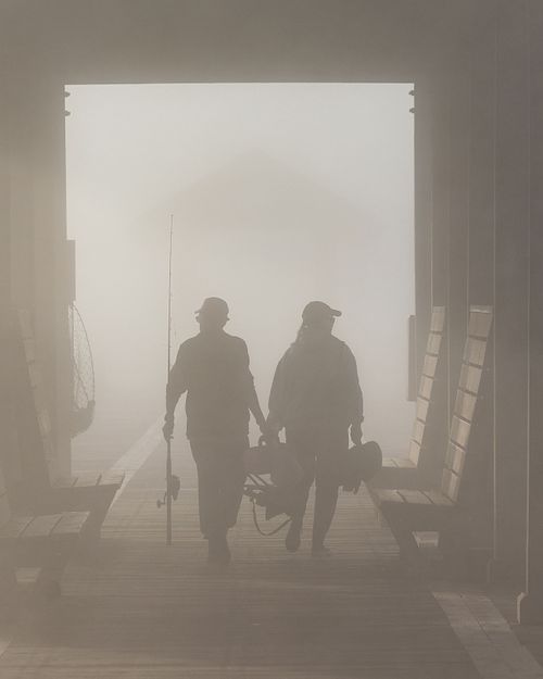 Silhouette of Fisherman Headed Out On Pier in Morning Mist