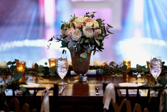 witte bloemen in een heldere glazen vaas op een bruine houten tafel